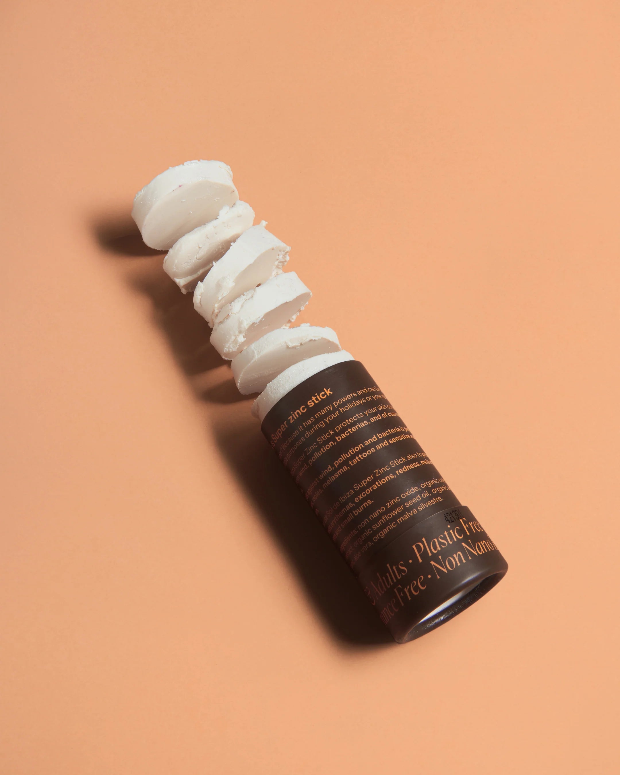 Open SPF30 mineral sunscreen stick with visible balm, in a compostable cardboard tube, shown on a peach background.