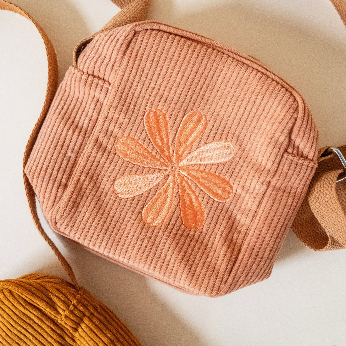 Corduroy dusty pink pouch with a floral embroidery on a light background