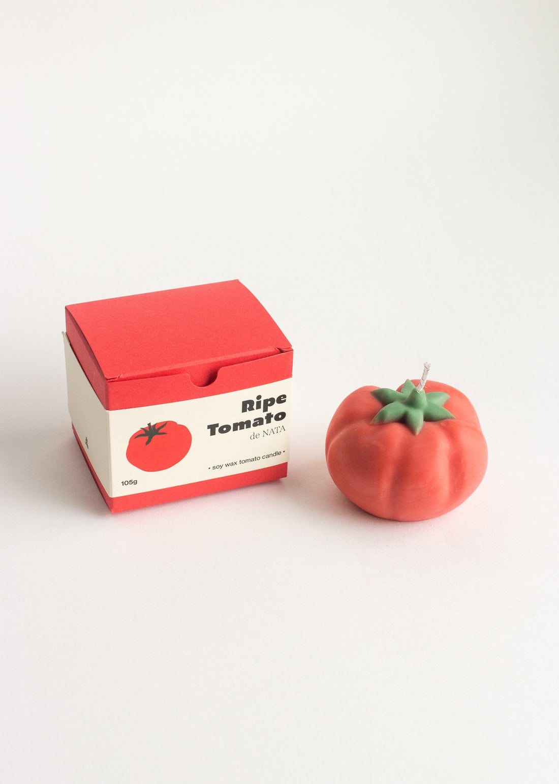 Tomato-shaped candle and packaging on a white background