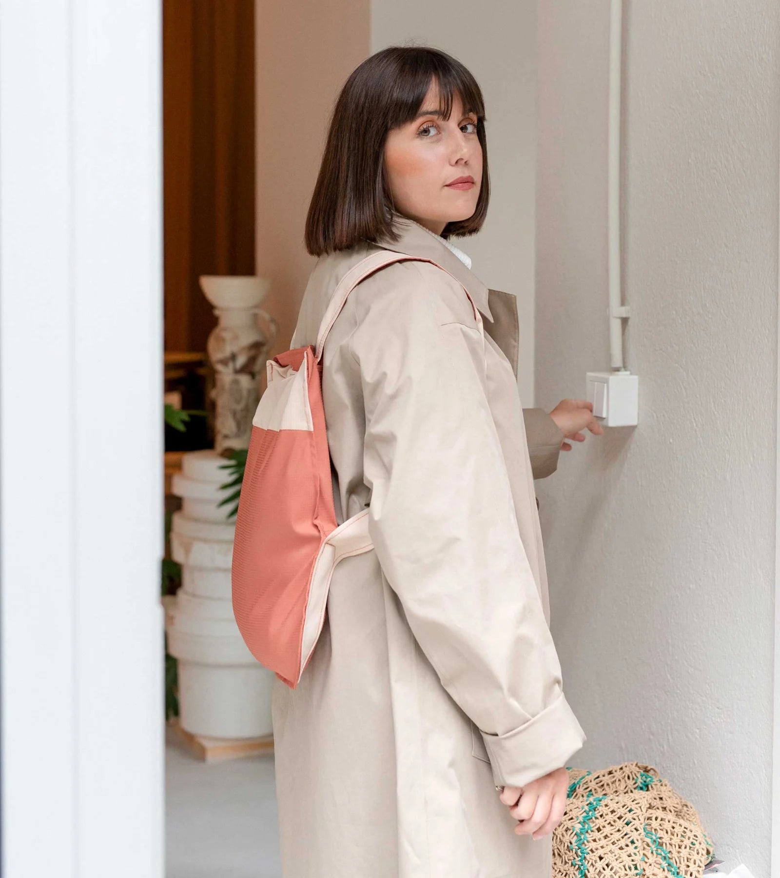 A person wearing the foldable sand & terracotta bag & backpack