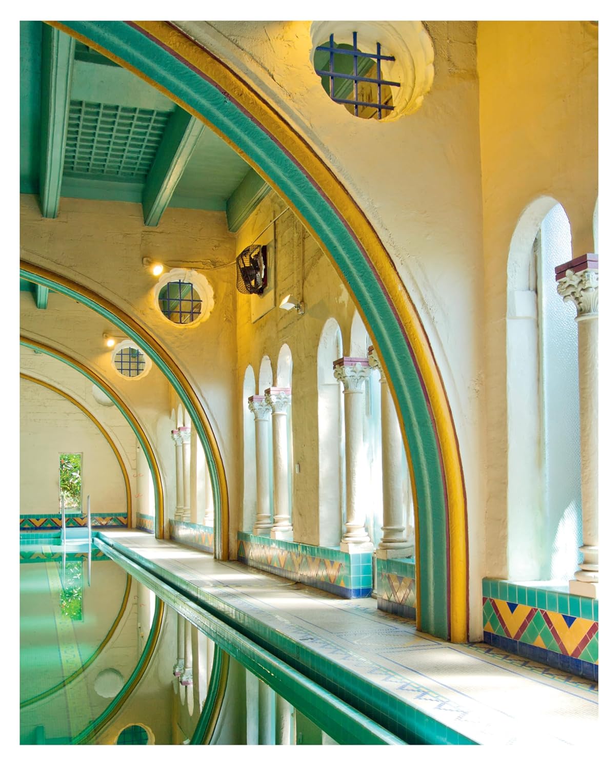 Colorful indoor pool with arched architecture and decorative tiles.