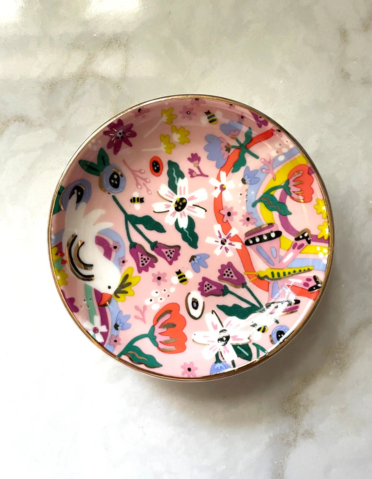 Butterfly garden porcelain trinket dish with colorful floral and abstract designs on a marble surface
