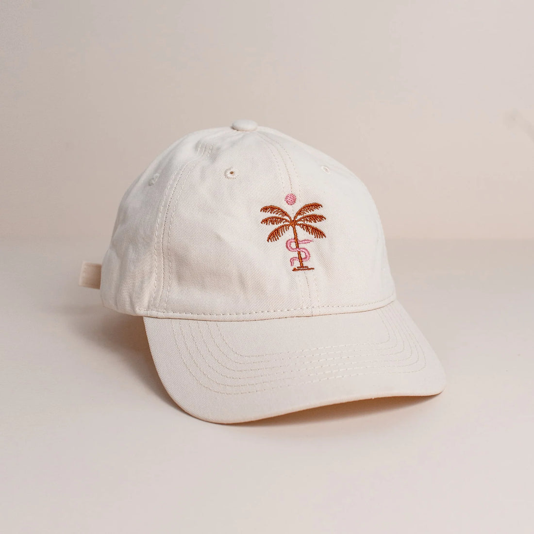 Off White cap with a copper palm tree design on a beige background