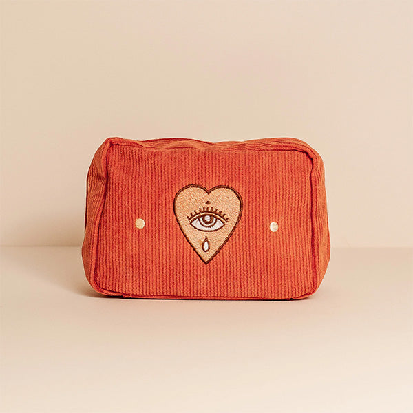 A rectangular makeup bag in orange with a bold sun design embroidered on the front and a double zip fastening.