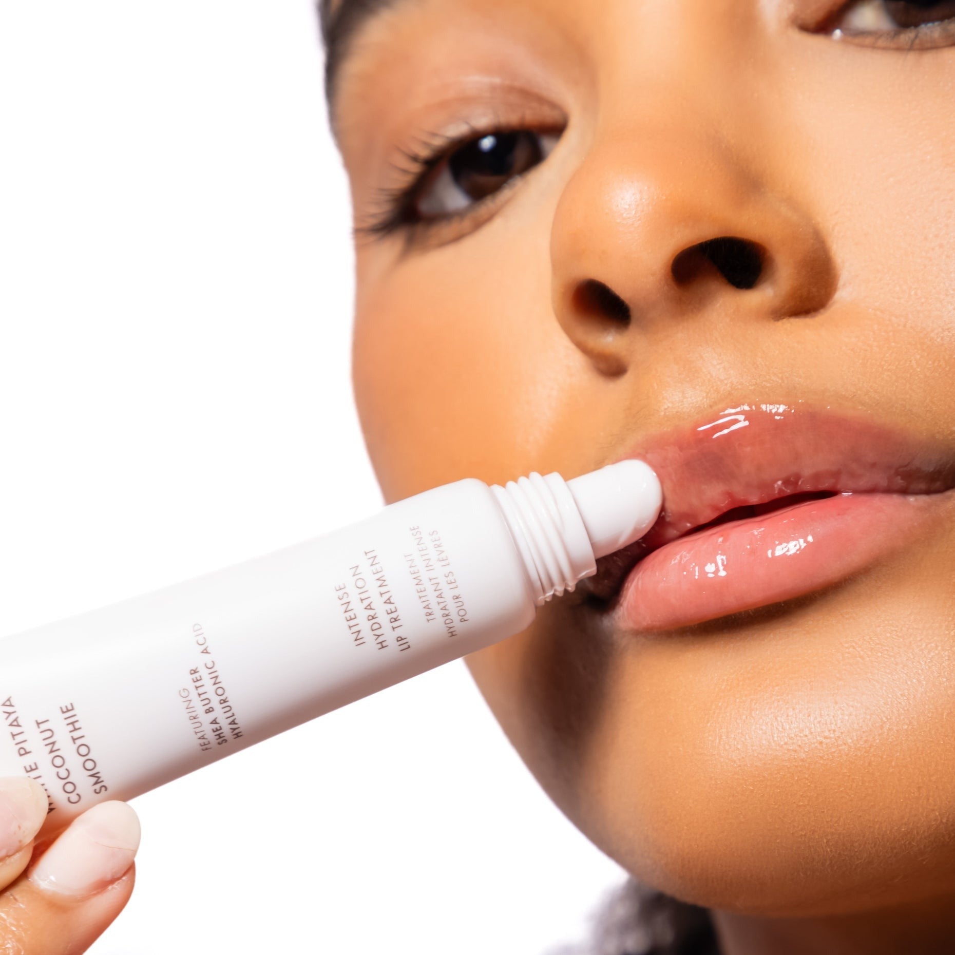Woman applying the White Pitaya Coconut lip balm to their lips with a close-up focus on the product.