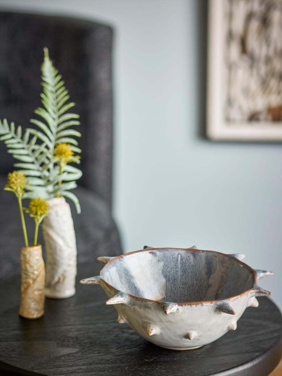 Edie Ceramic bowl , with a vase of plants in the background.