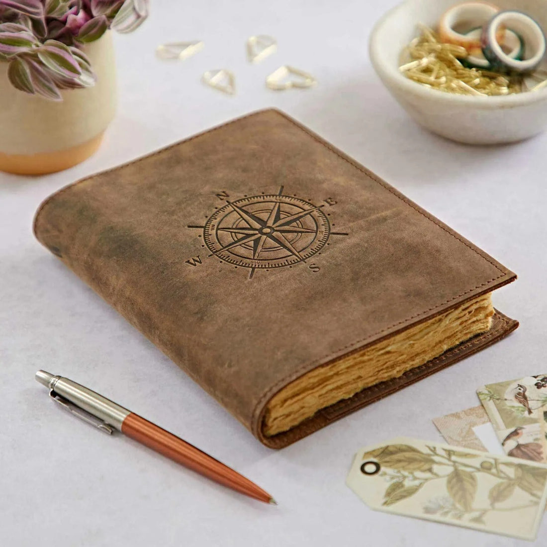 Compass Leather Journal with a pen placed nearby, highlighting its vintage leather cover and handcrafted khadda paper