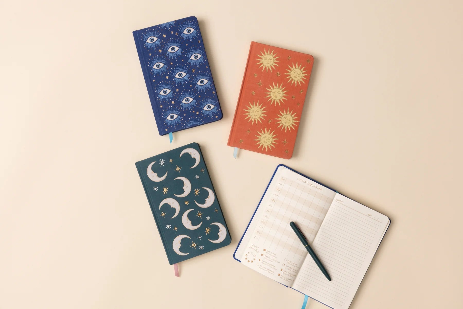 Four celestial notebooks with different designs on a beige background