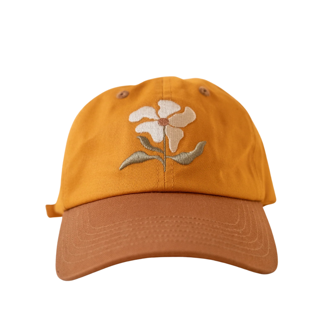 Yellow cap with a white flower design on the front against a white background