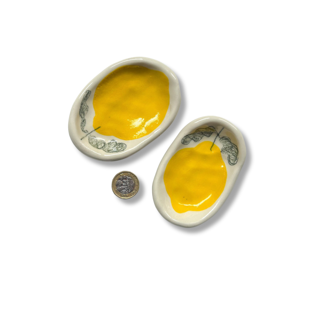 Small hand-painted stoneware trinket dishes featuring a vibrant lemon motif, perfect for holding rings, soap, or spices.
