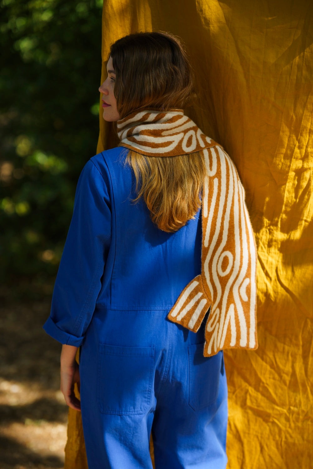 Person wearing a blue outfit and ochre leaf patterned scarf