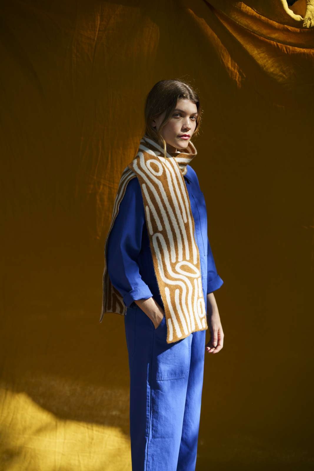 Person wearing a blue outfit and ochre leaf patterned scarf