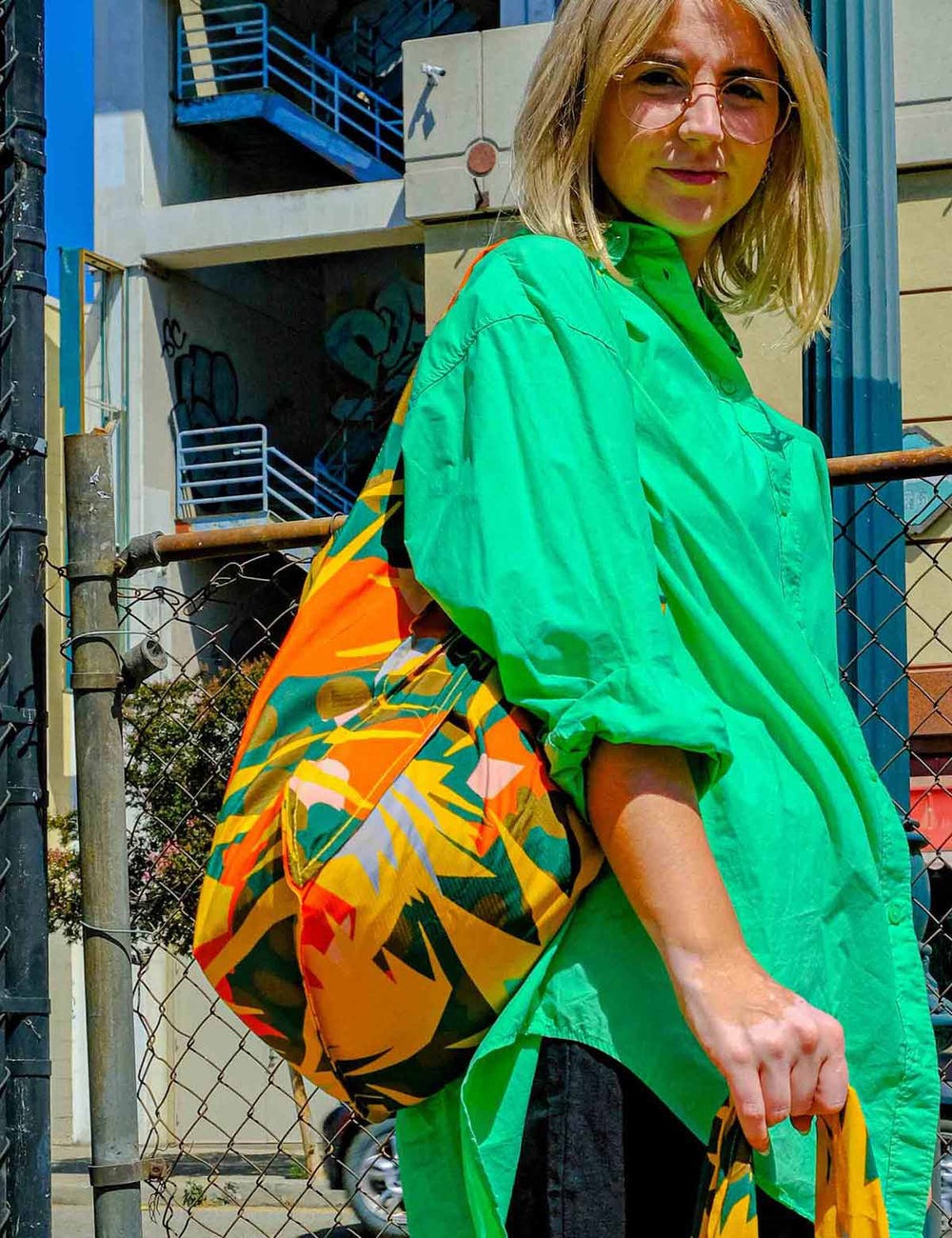 A person wearing a multicolored Notabag Spark Bag & Backpack with a floral pattern.