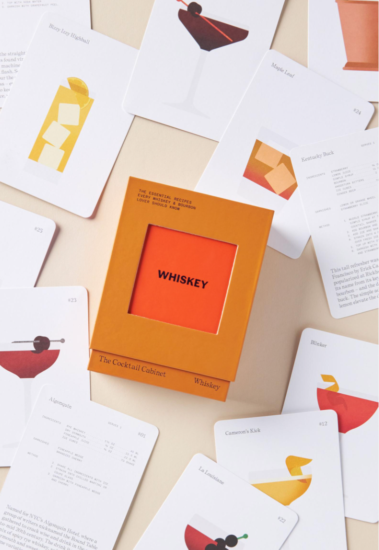 The Cocktail Cabinet: Whiskey recipe deck centered on a grey surface with cocktail cards spread around