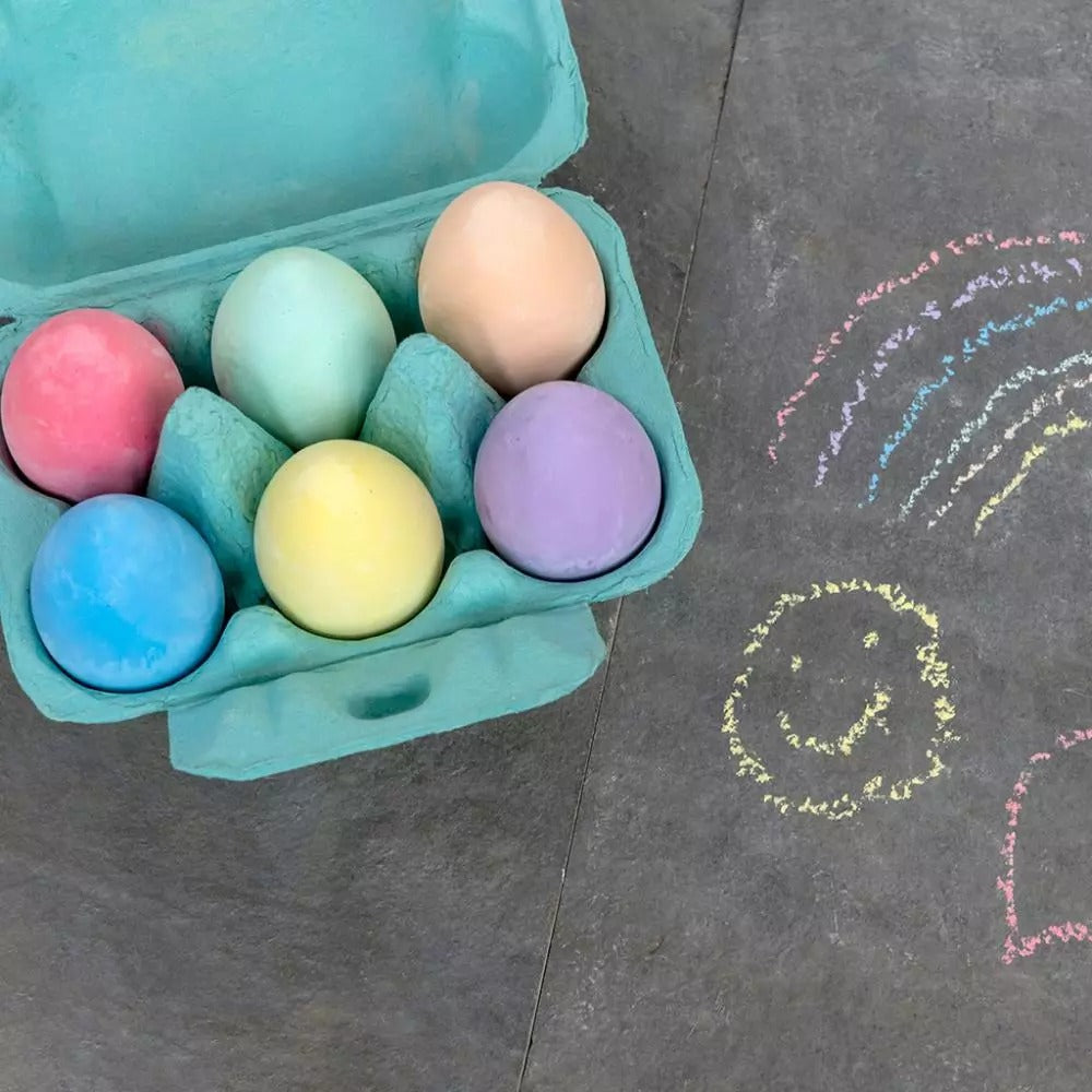 Colourful egg-shaped chalks in cardboard egg box for kids’ art on a charcoal background