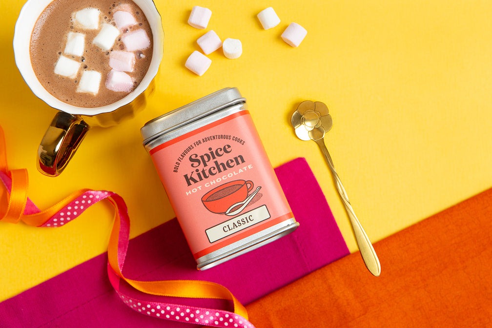 Spice Kitchen classic hot chocolate with mug, and marshmallow on orange and pink surface and yellow background – vegan dairy-free hot chocolate.