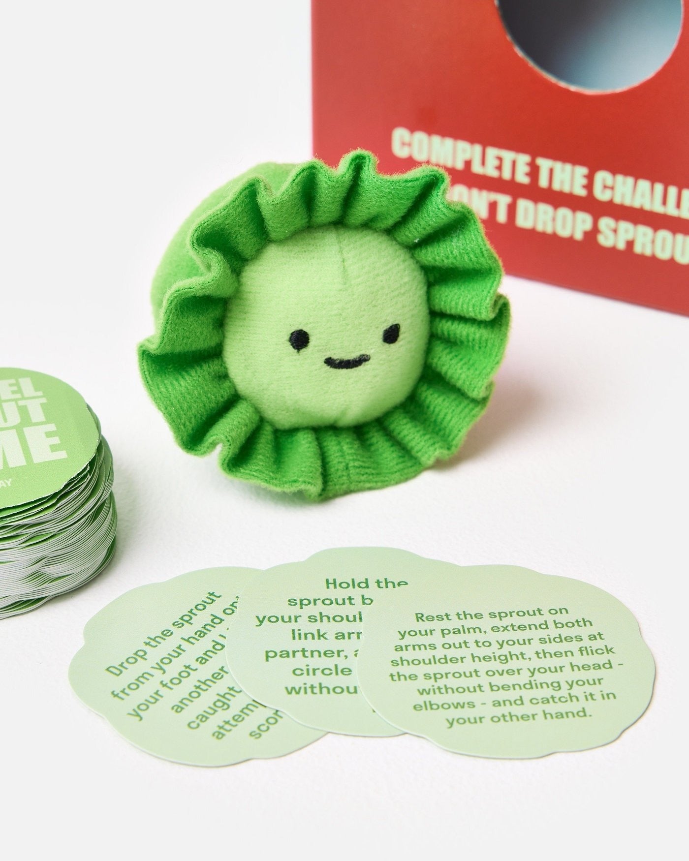 Green sprout toy with game cards on a white background