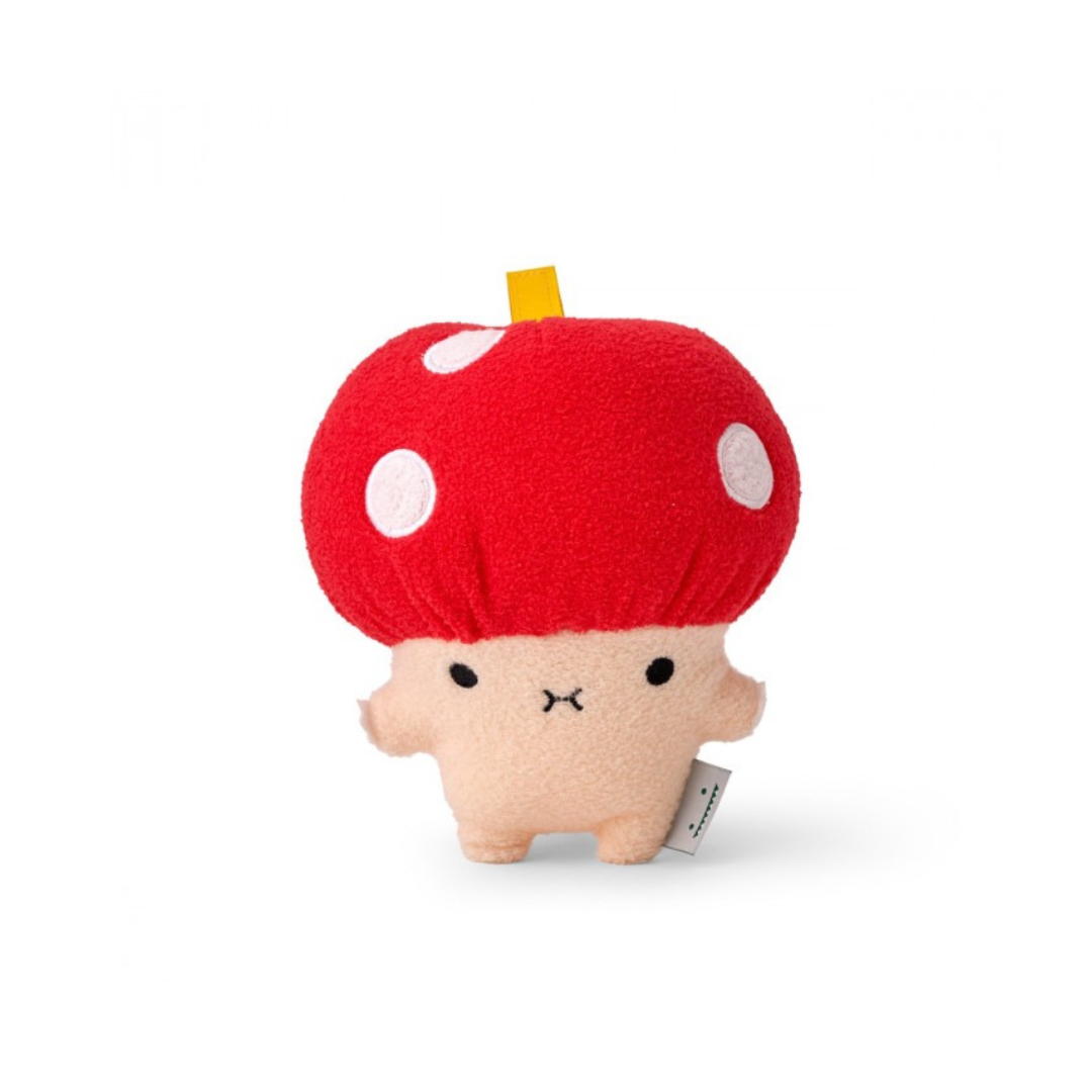 A plush toy resembling a mushroom with a beige body and a bright red cap with white spots. It has an embroidered face and a small yellow tag on its cap.
