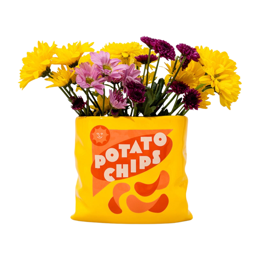 A ceramic vase designed to resemble a potato chips bag, filled with colorful flowers, against a white background.