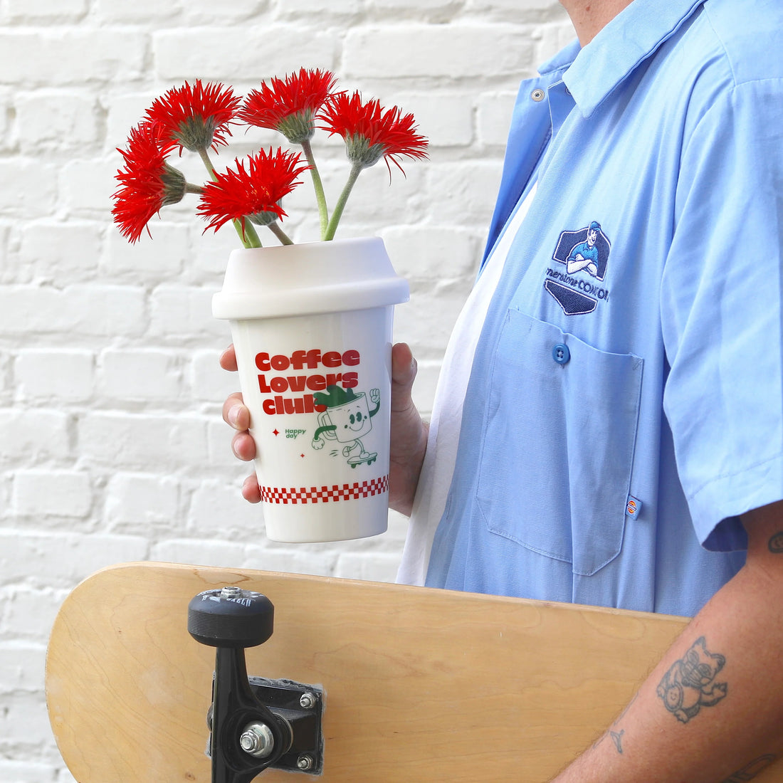 A white ceramic cup with a red and green graphic that includes a coffee mug and the text &