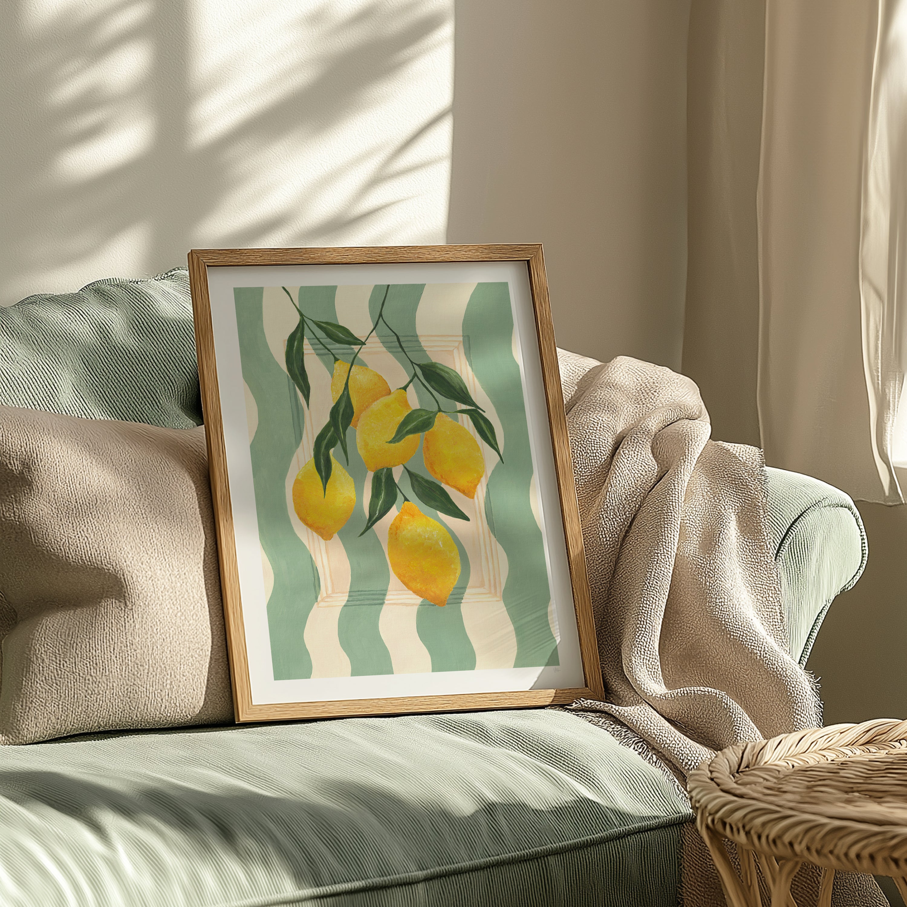 Framed artwork of lemons on a sage and cream striped background on a sofa.