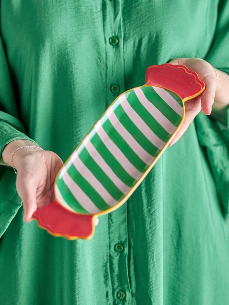 Person holding Striped Green Caramella-shaped serving plate against a green shirt background