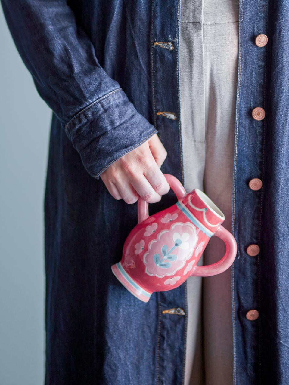 A person holding the red Odina Decorative Vase ceramic vase with dual handles and hand-painted floral design in blue, pink, and white – Odina Decorative Vase