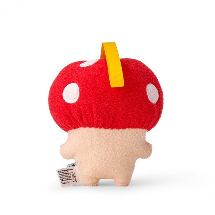 A plush toy resembling a mushroom with a beige body and a bright red cap with white spots. It has an embroidered face and a small yellow tag on its cap.