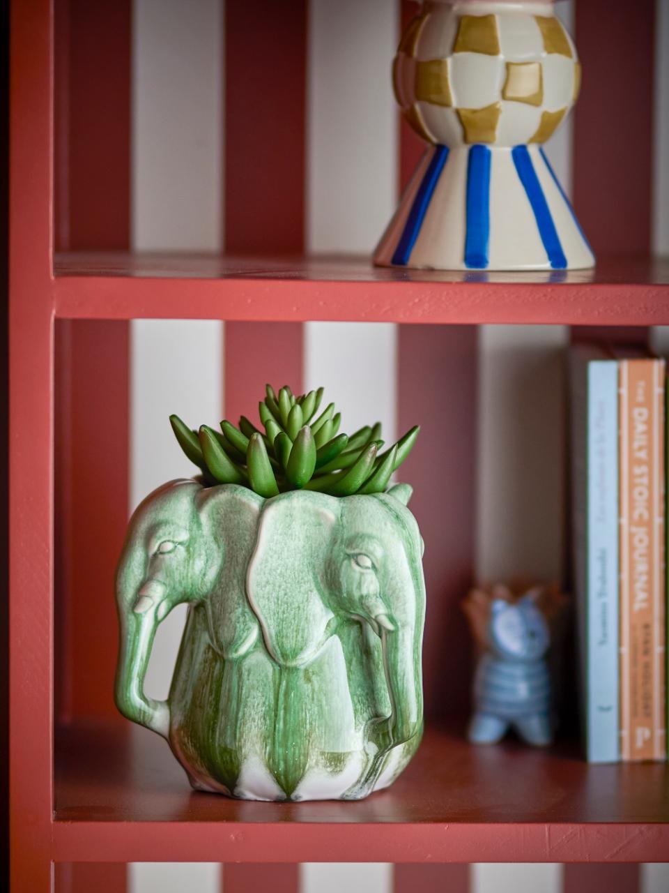 Green ceramic elephant planter with succulents on a red shelf