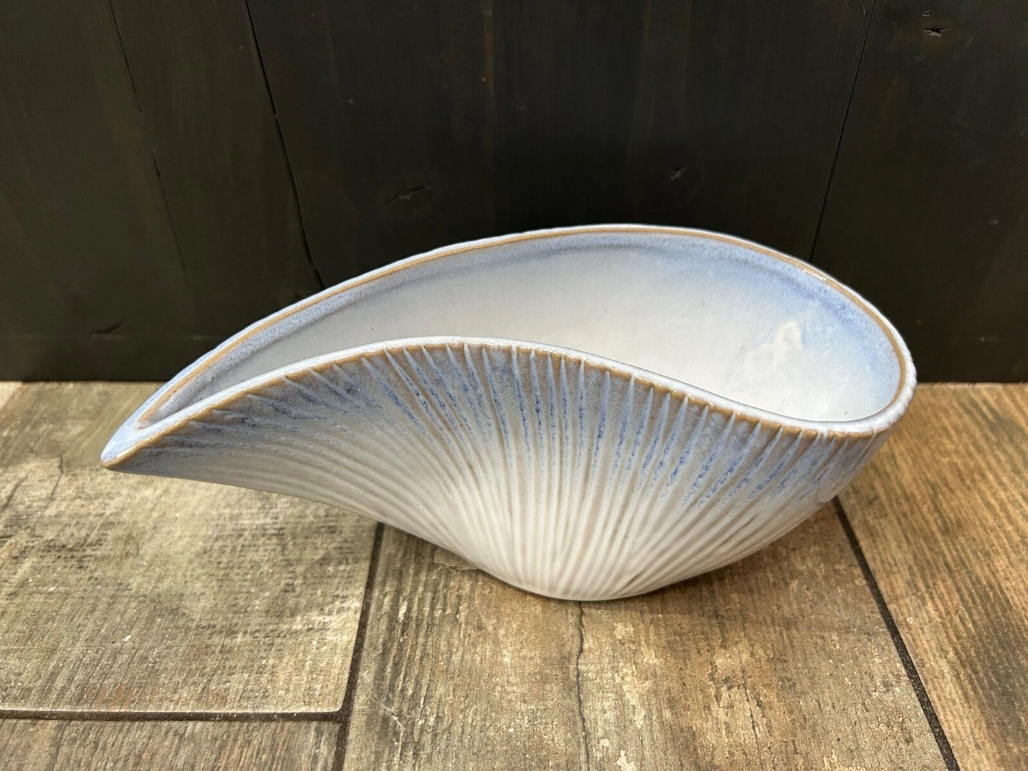 Side view of the Blue ombre stoneware shell bowl with seashell-inspired design, decorative coastal-style centrepiece for home décor on a wooden surface