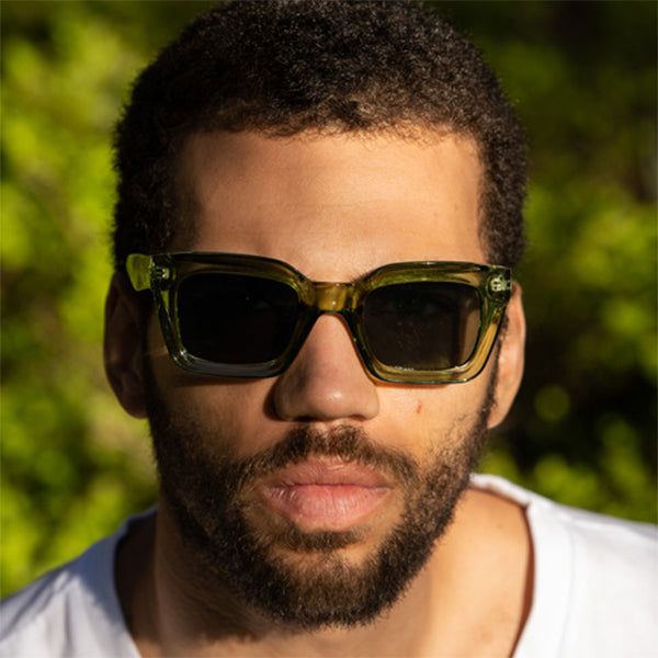 A man wearing the Anna Green Sunglasses – Unisex square-frame sunglasses with forest green frame and green UV400 lenses, medium-large fit, made from recycled plastic.