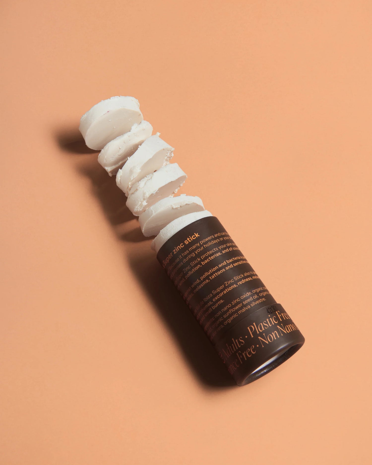 Open SPF30 mineral sunscreen stick with visible balm, in a compostable cardboard tube, shown on a peach background.