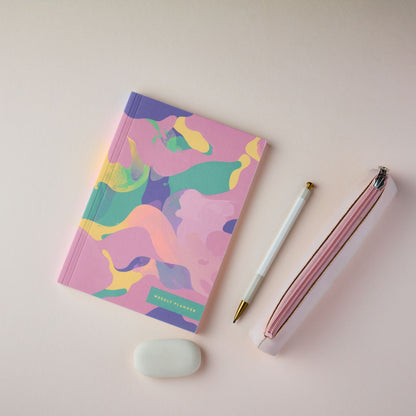 The Reverie A5 Weekly Planner Pink Marble with a pen and eraser on a light pink background