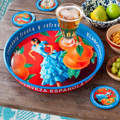 Decorative tray with Spanish-themed design featuring a woman in a blue dress and oranges, accompanied by a glass of beer on a wooden table.