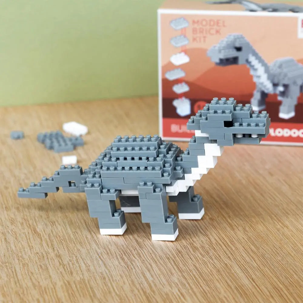 Grey Diplodocus Dinosaur Brick Building Kit  with the packaging on a wooden surface with a box in the background.
