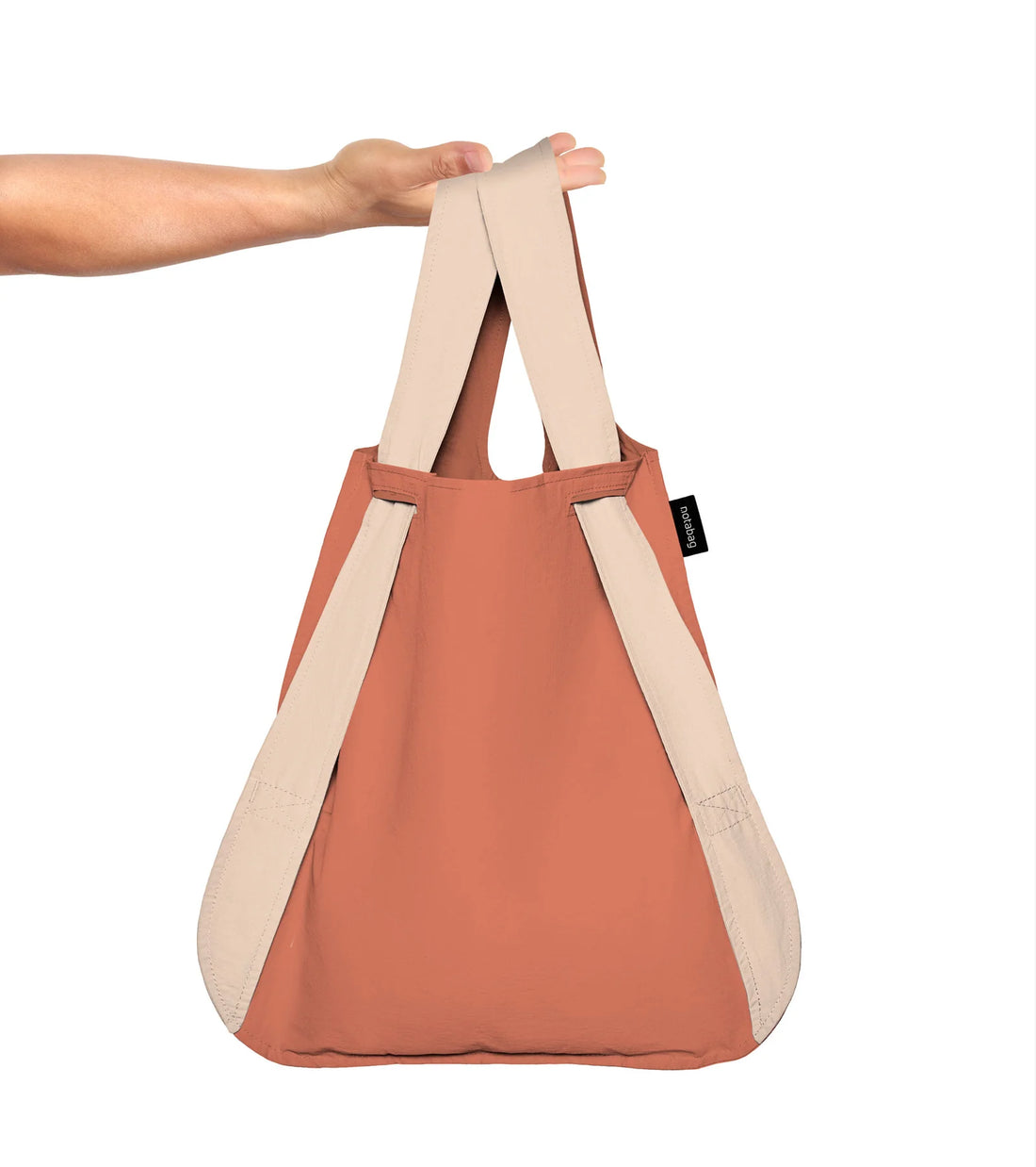 A person holding a sand and terracotta foldable bag