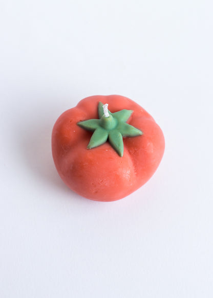 Red candle tomato-shaped with green stem on a white background