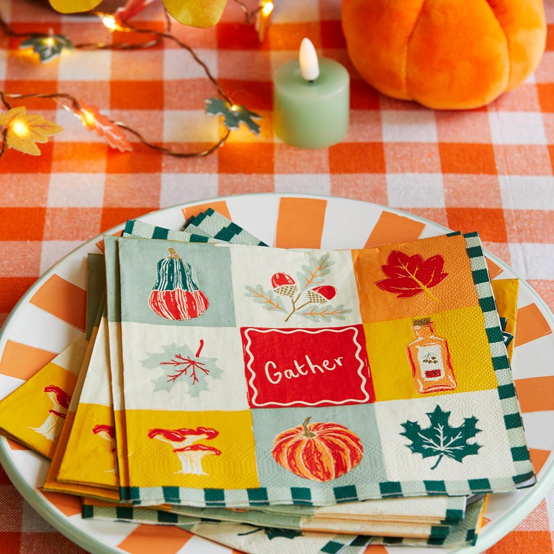 Stack of decorative napkins with autumn designs on a checkered tablecloth.