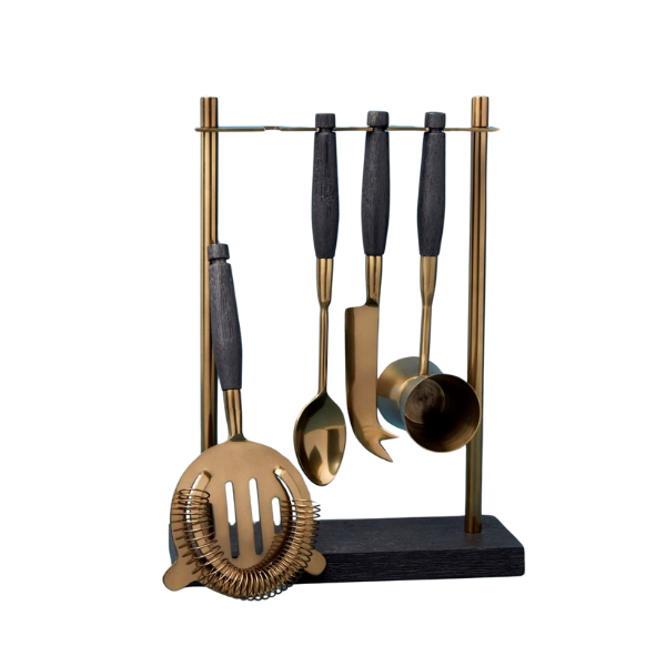 "Arendal aged bronze hanging bar tool set with strainer, measuring cup, knife, and spoon alongside handcrafted mango wood bar set on white background"