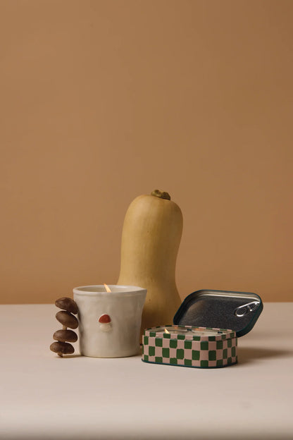 Butternut squash, ceramic mushroom candle, tin mushroom candle on a beige background