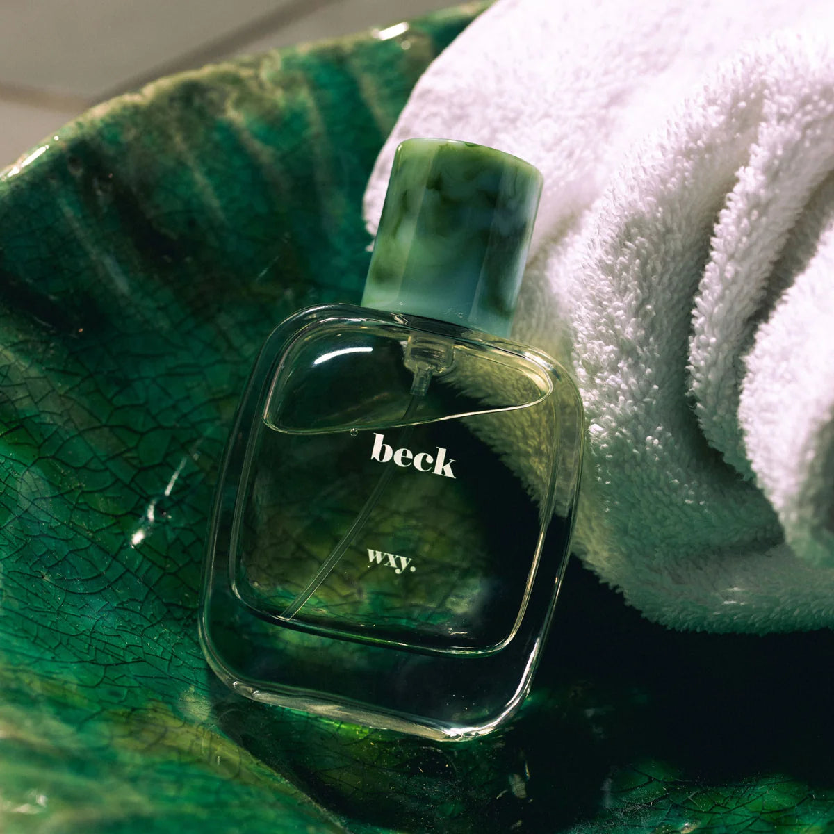 Beck Parfume inside a green bowl and next to a white towel