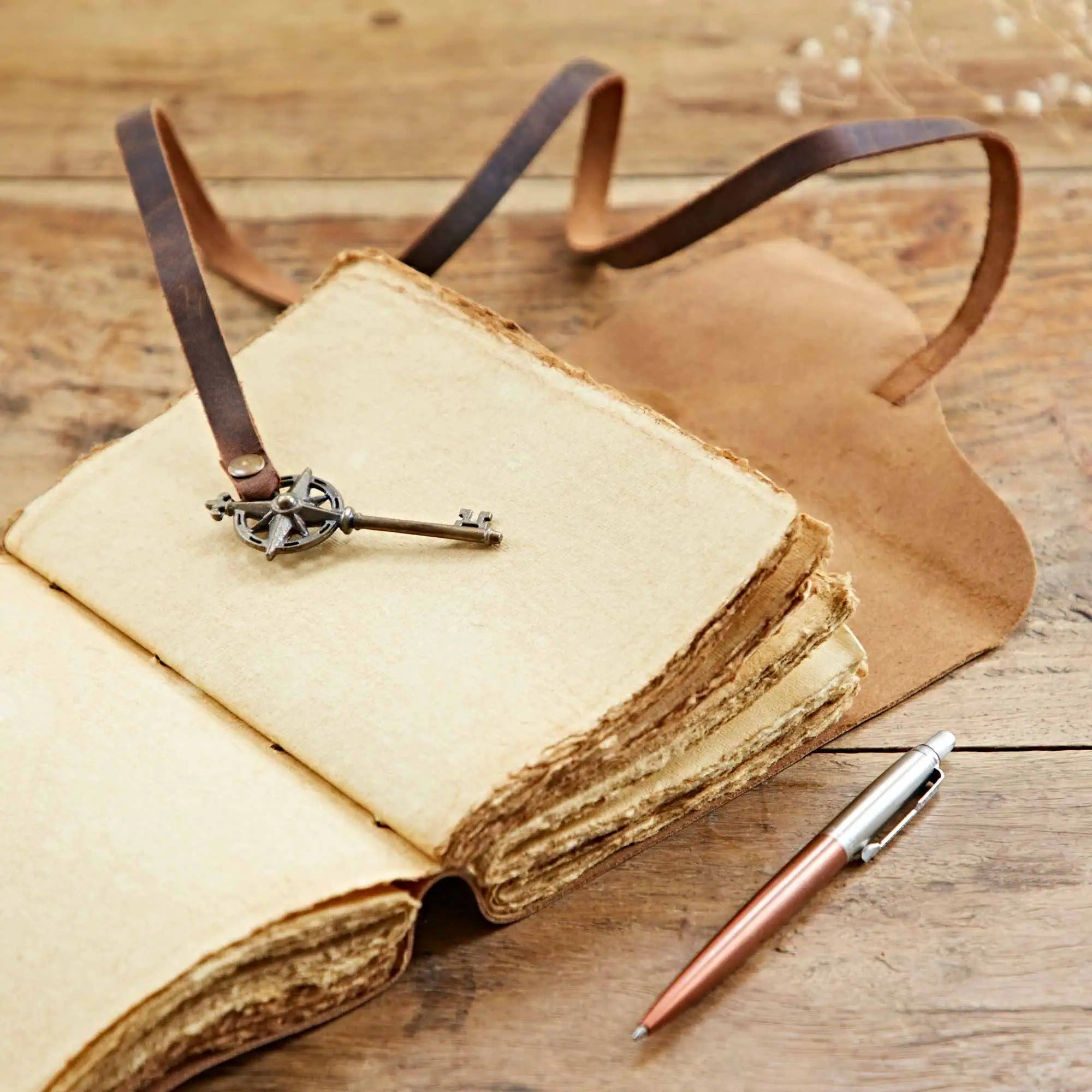 Open Dream Buffalo Leather Journal With A Key on a wooden surface, showing unlined, dyed khadda paper and the antique compass key closure.