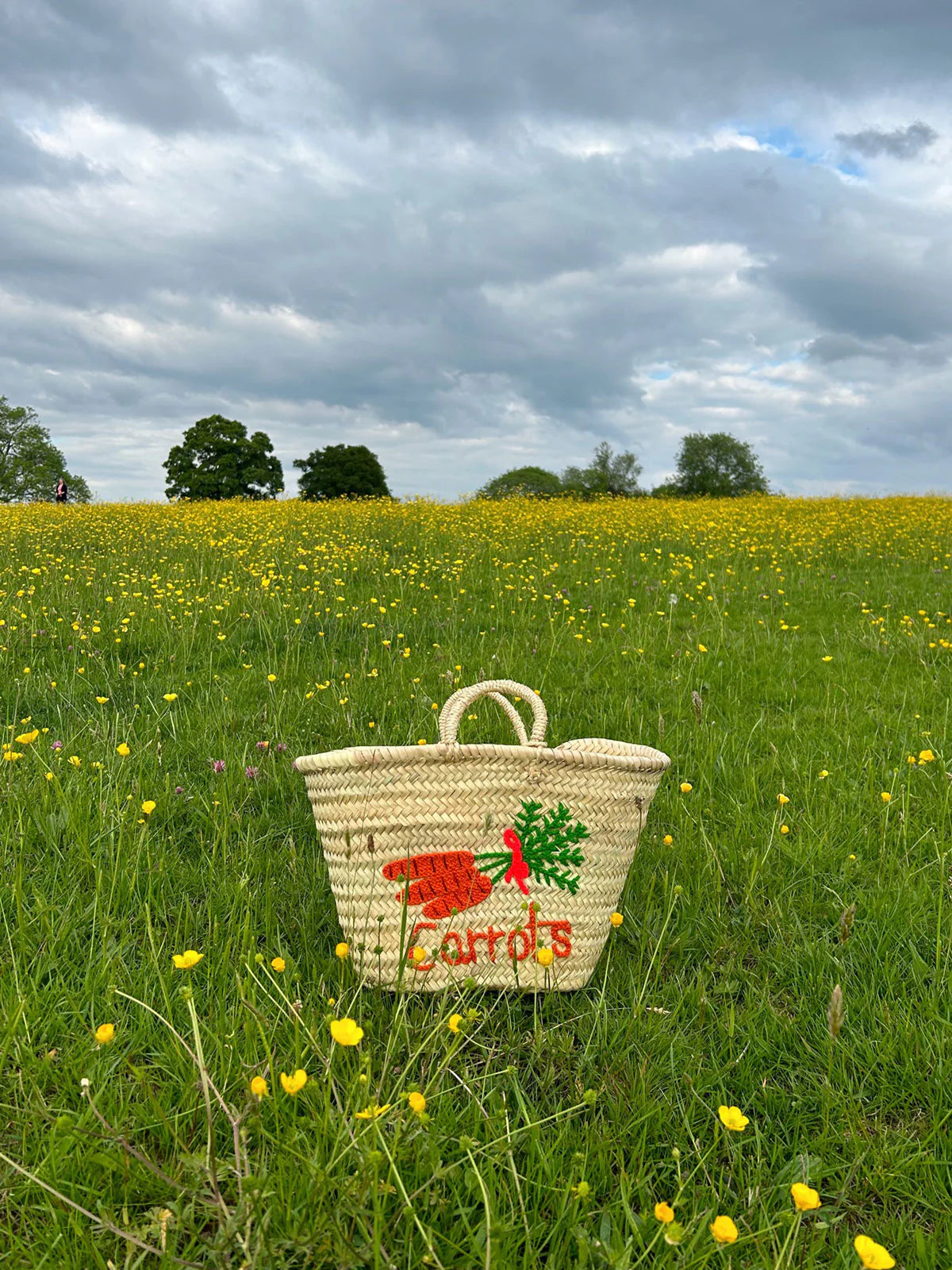 Handwoven palm leaf market basket with embroidered carrot design in the fields
