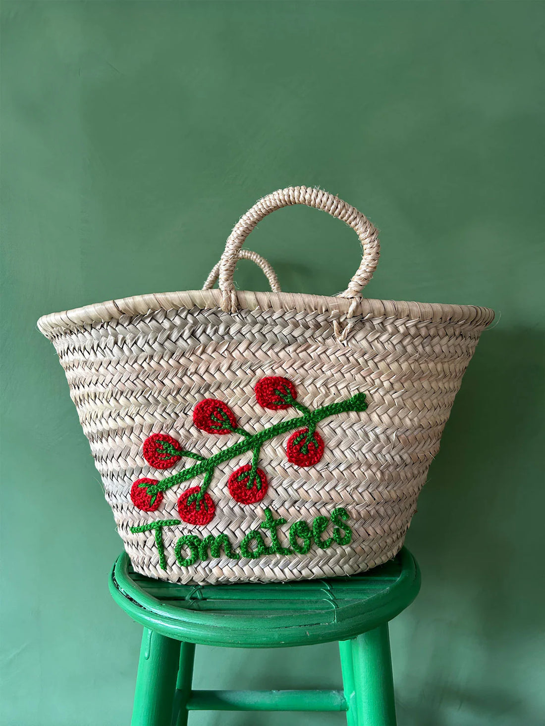 Handwoven palm leaf market basket with embroidered tomato vine design
