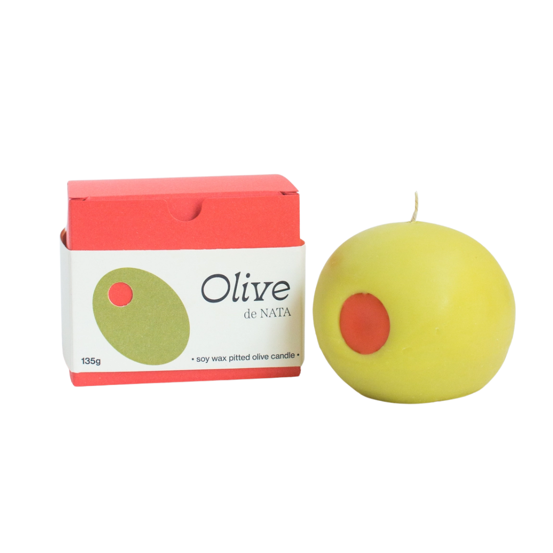 Green Olive candle with red center next to its packaging on a white background