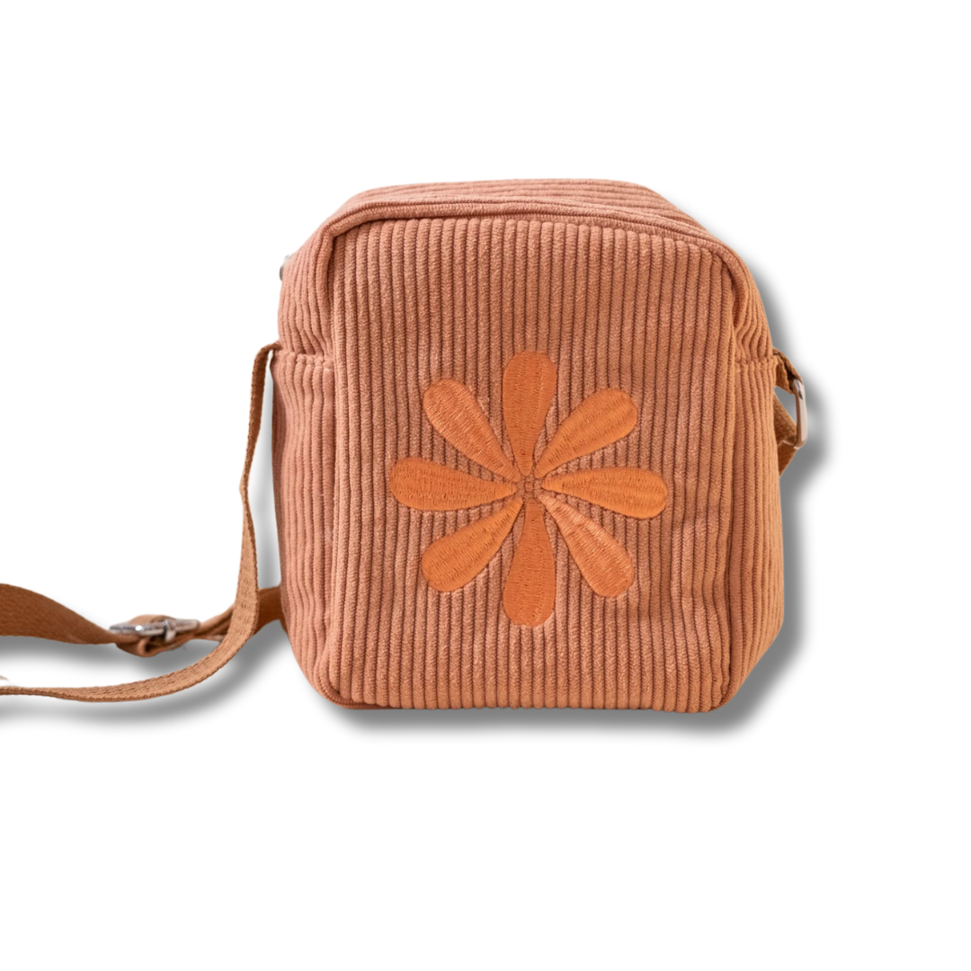 Dusty Pink corduroy crossbody bag with a flower embrodery design on the front against a white background