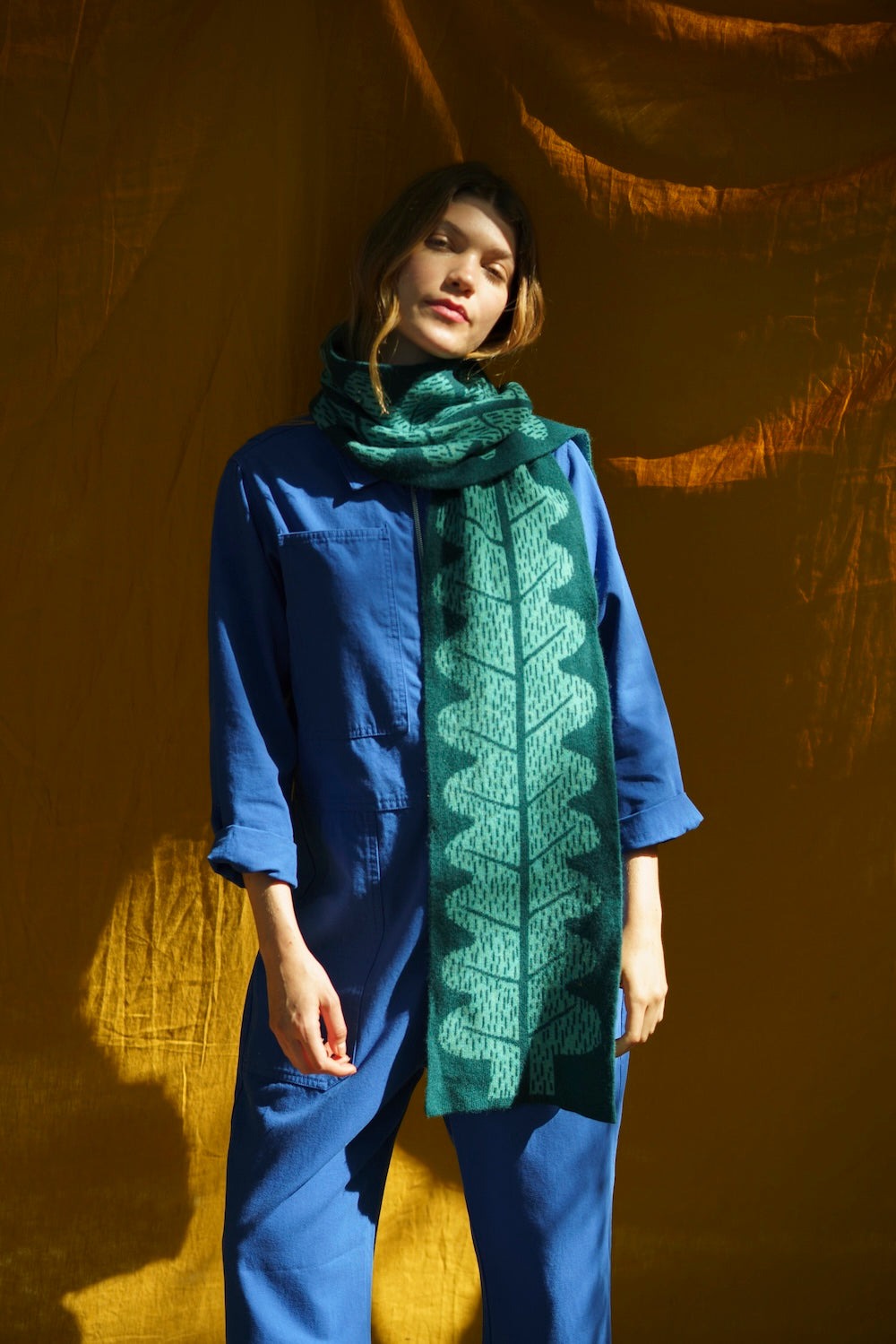 Person wearing a blue outfit and green leaf patterned scarf