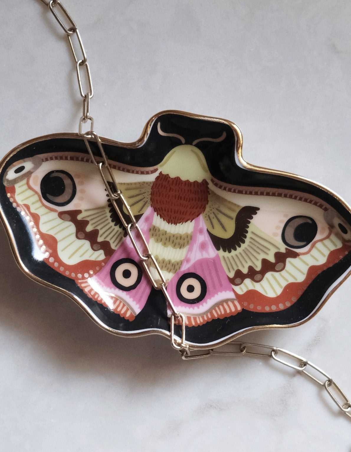 Butterfly-shaped trinket dish with a chain inside on a light background