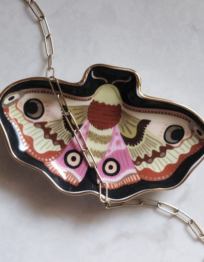 Butterfly-shaped trinket dish with a chain inside on a light background