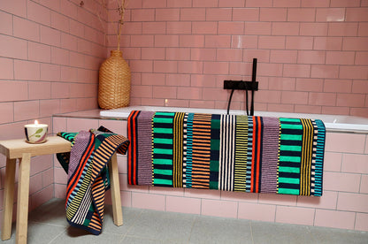 Multi Stripes Hand Towel and Multi Stripes Bath Towel with, colorful playful design, in a pink bathroom